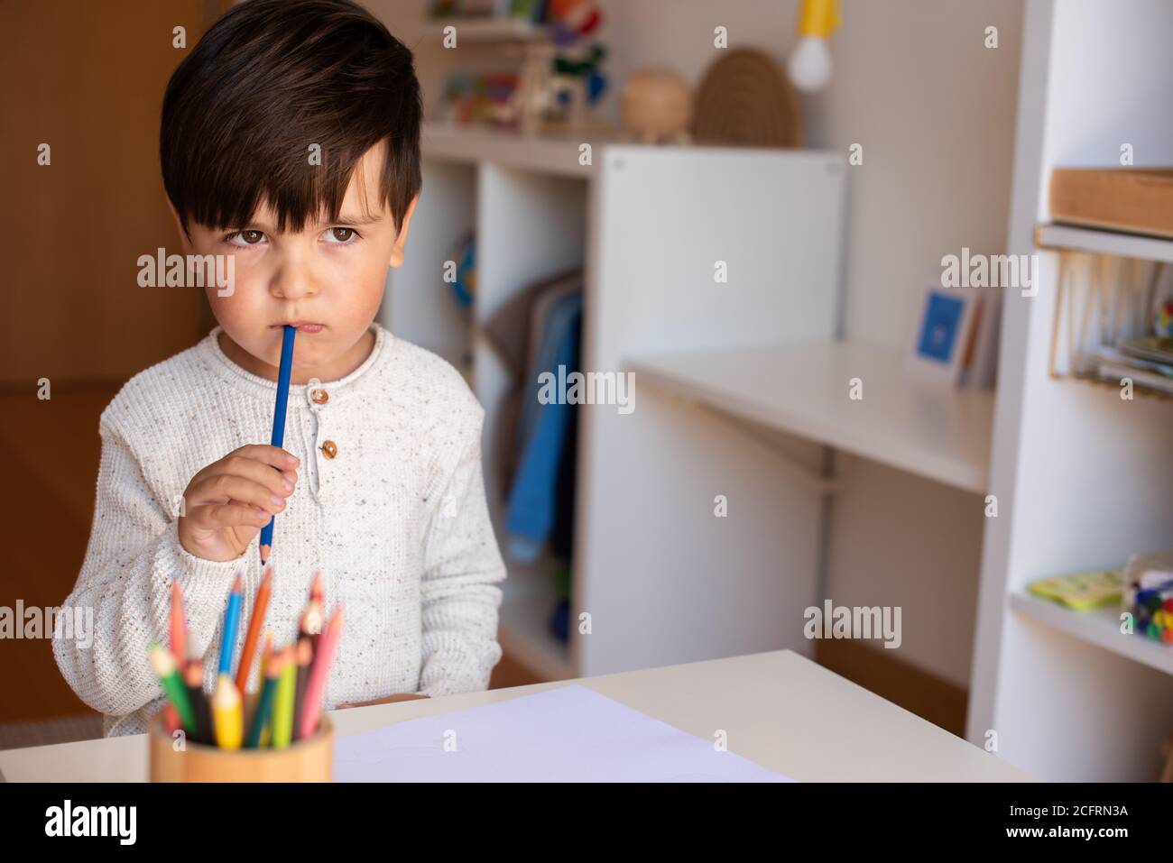 Little preschooler kid drawing with coloured pencils. Homeschooling. Learning community. Montessori school. Stock Photo