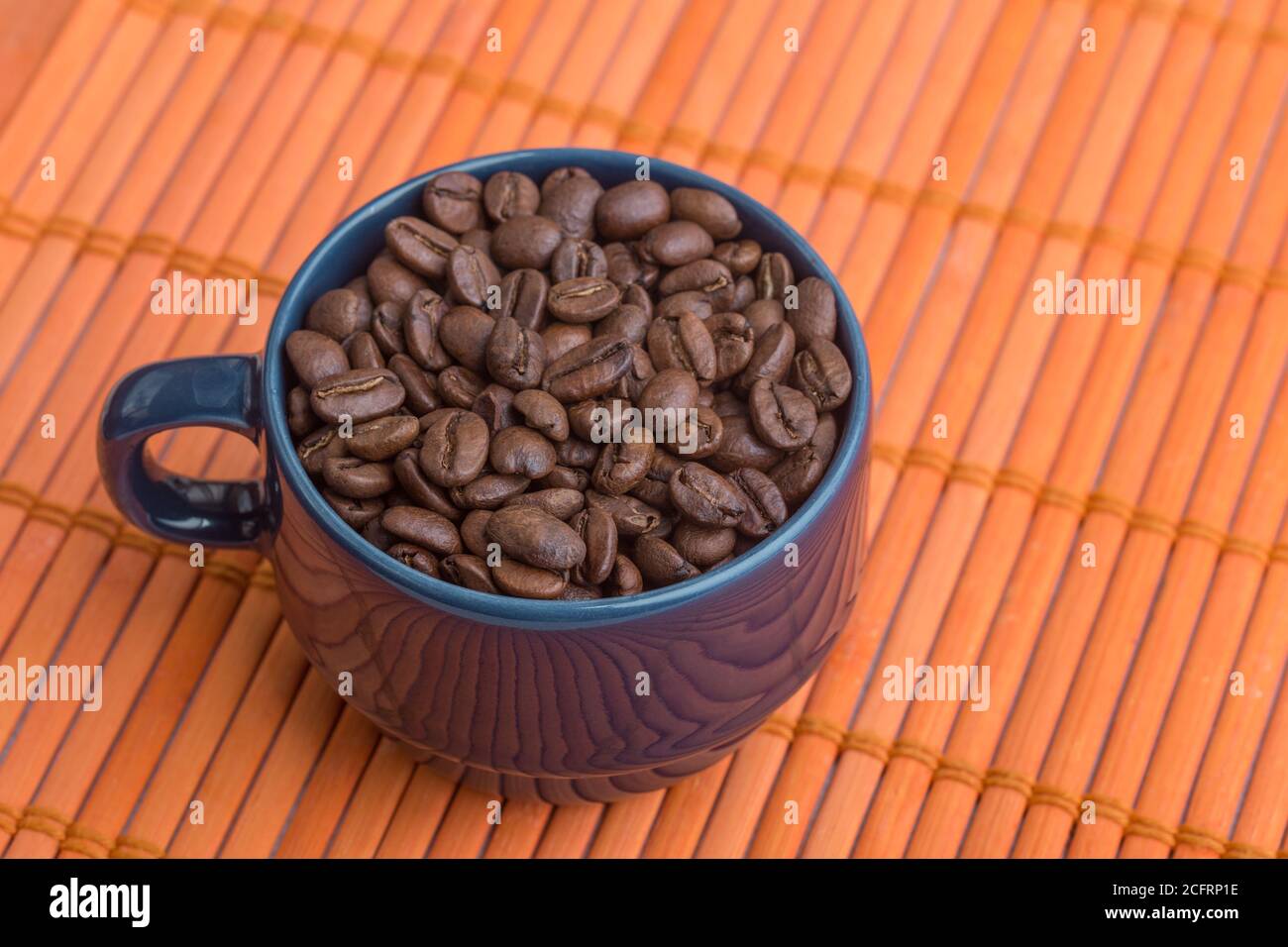 blue mug with coffee beans on an orange texture, studio Stock Photo