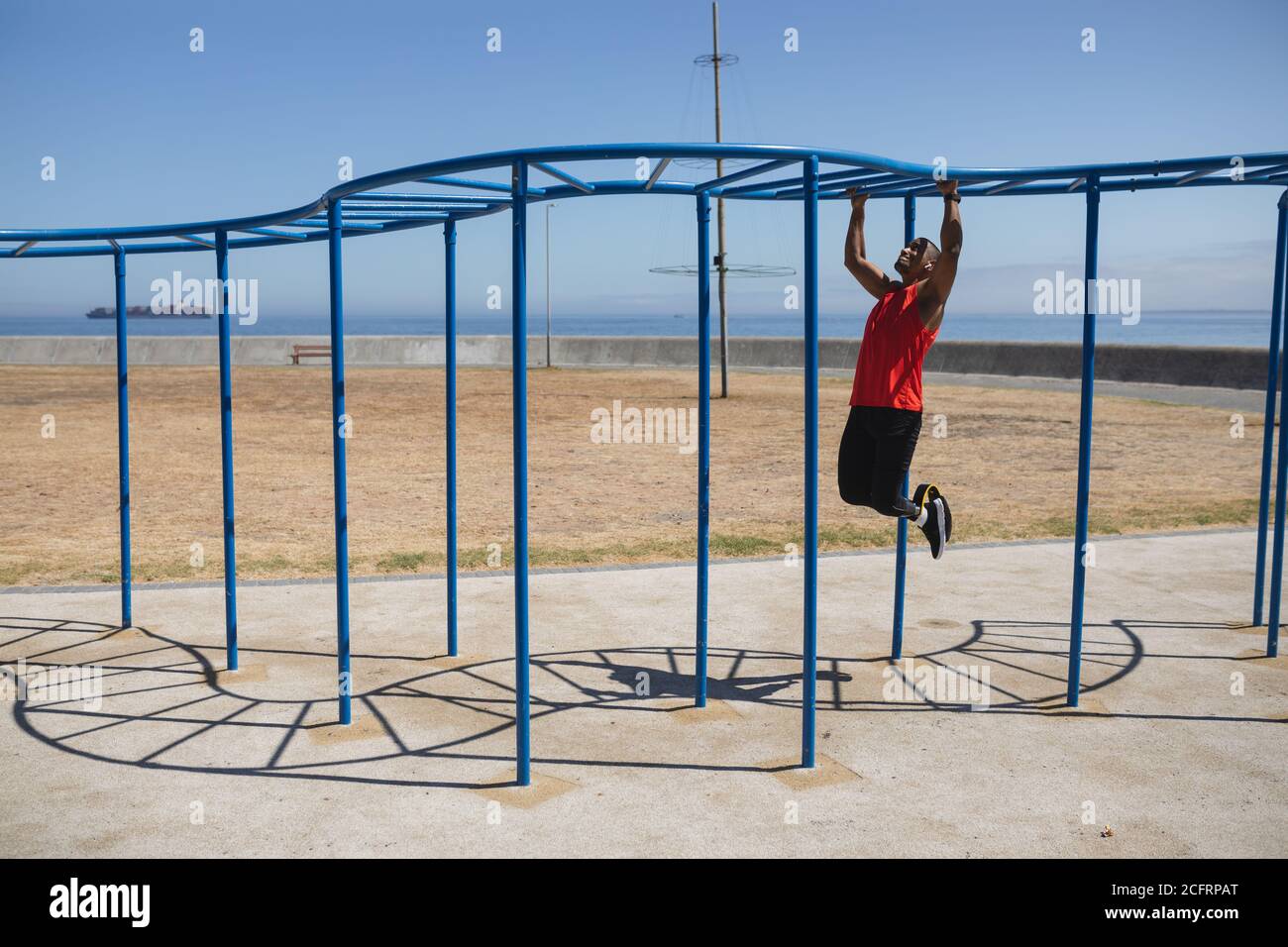 Man with prosthetic leg working out on monkey bars in the park Stock