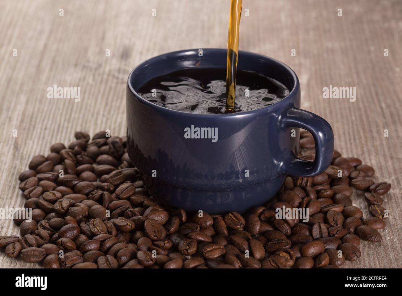 putting coffee in a blue cup with espresso and around with coffee beans