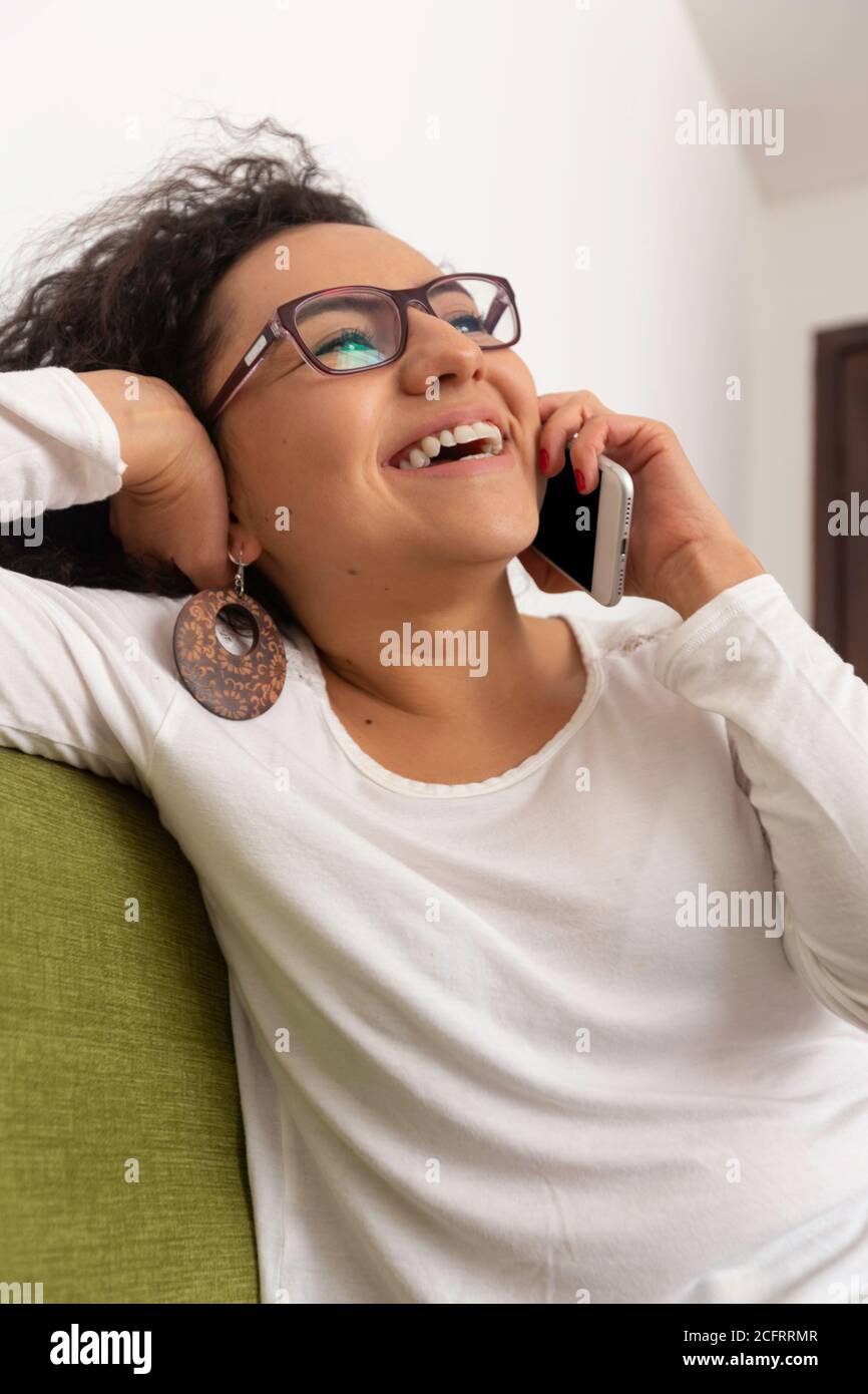 young woman with curly hair talking on the phone in an office Stock Photo