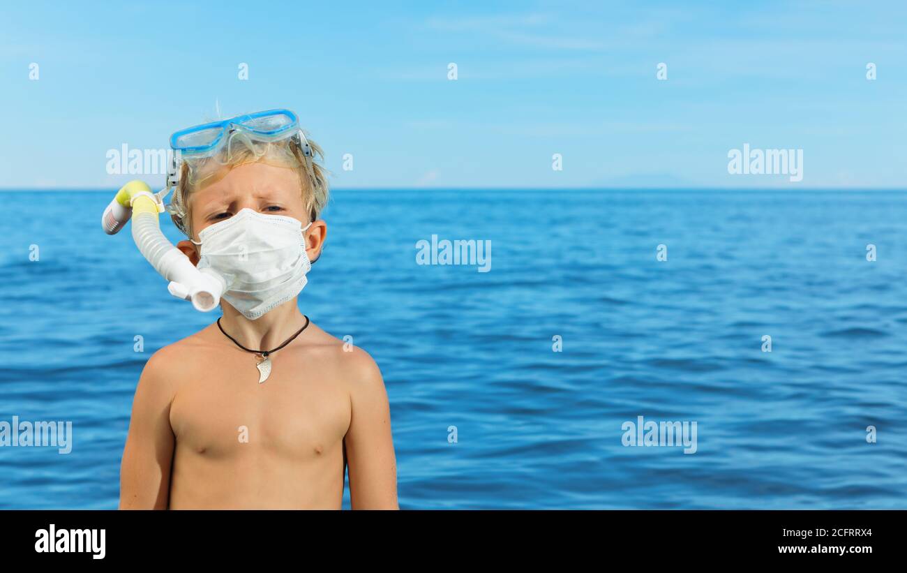 Boy in snorkeling mask wear surgical face mask on sea beach. Cancelled cruises, tours due coronavirus COVID 19 world epidemic. Stock Photo