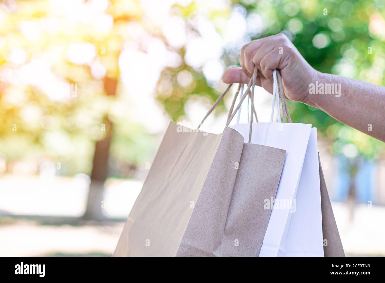 Female delivery courier holds paper bags with groceries to send to customer home. Stock Photo