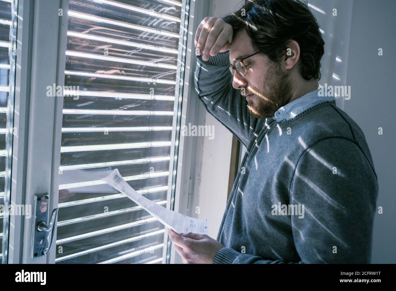 Frustrated disappointed guy reading a financial letter at home Stock Photo