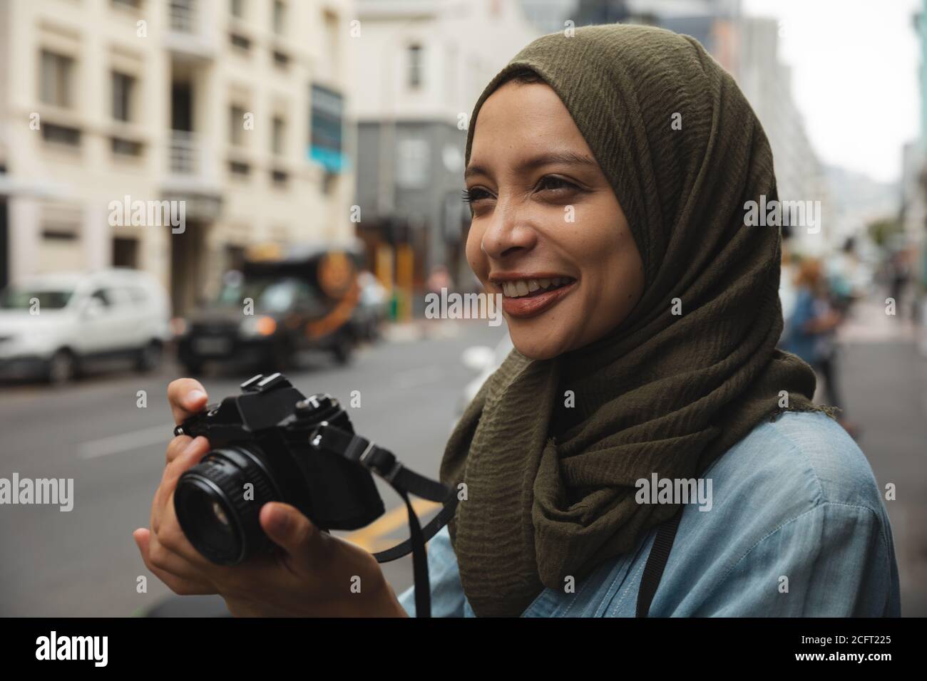 Woman in hijab taking photos using digital camera on the street Stock Photo