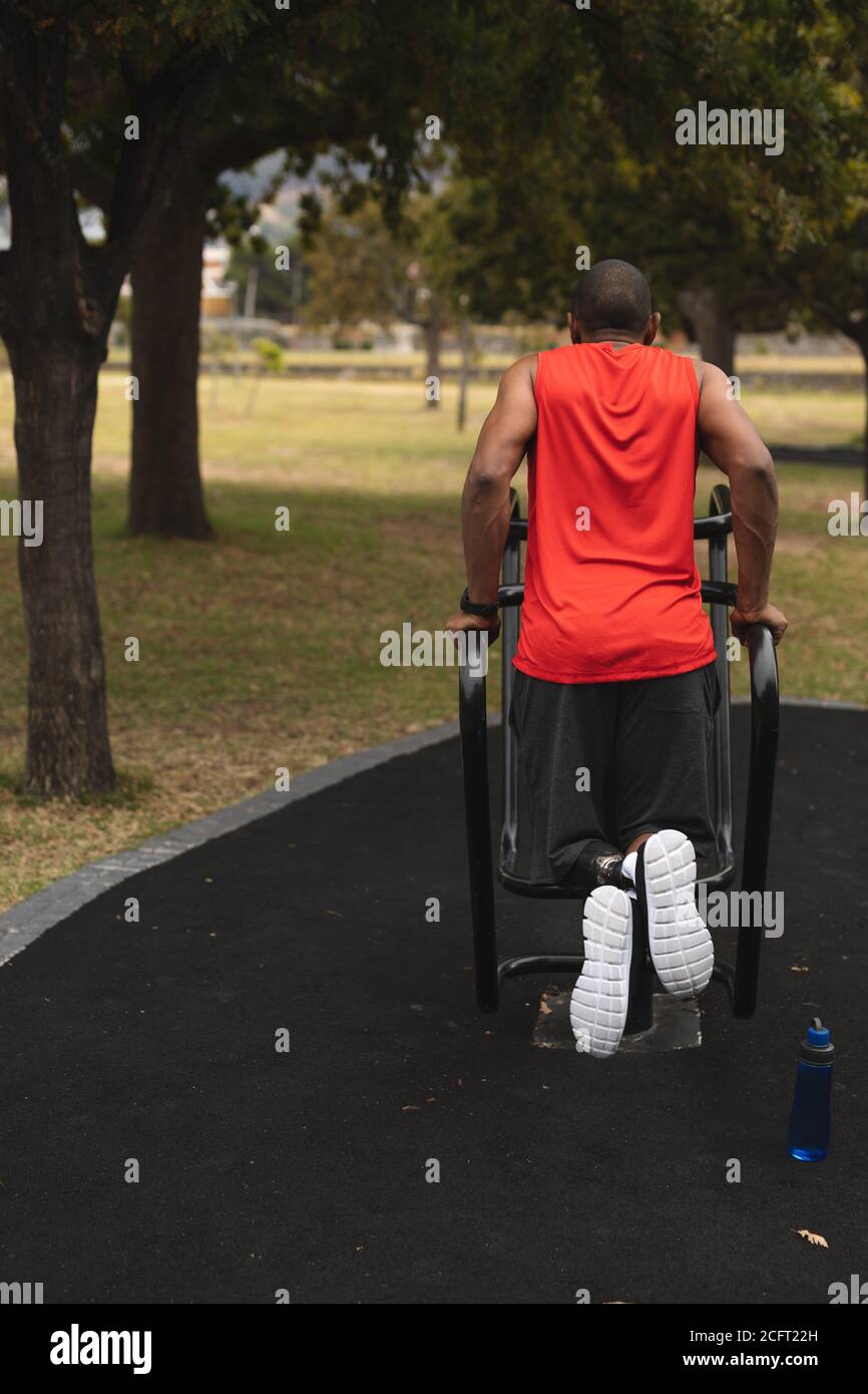 Rear view of man with prosthetic leg performing dips exercise in the park Stock Photo