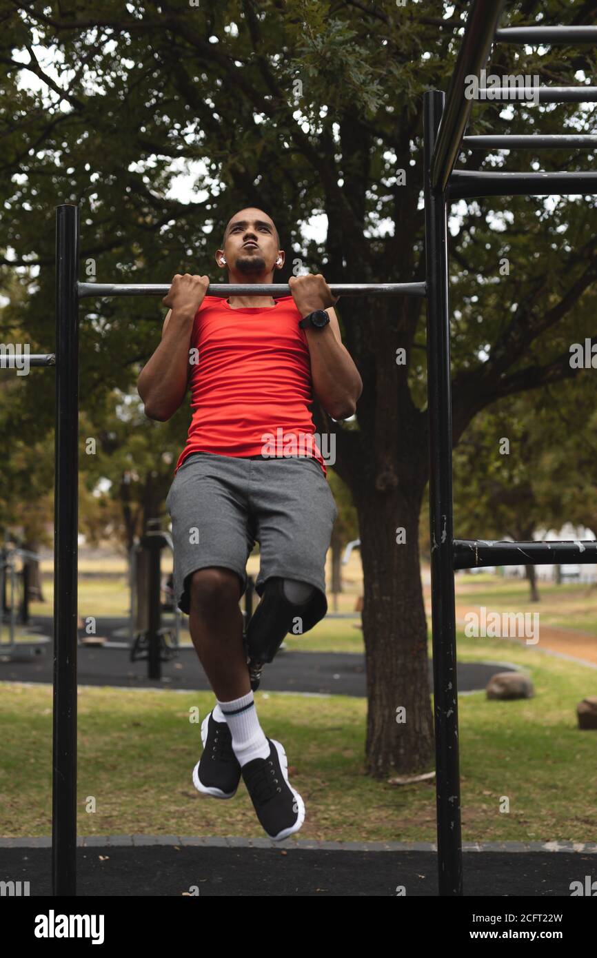 Man with prosthetic leg performing pull ups exercise in the park Stock Photo
