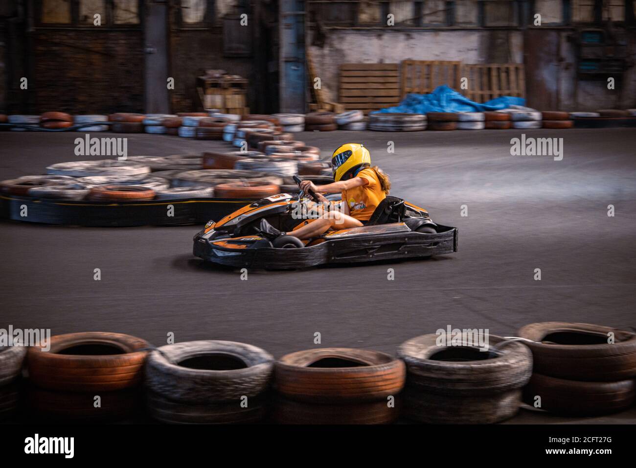 Girl driving a go kart at an indoor track Stock Photo