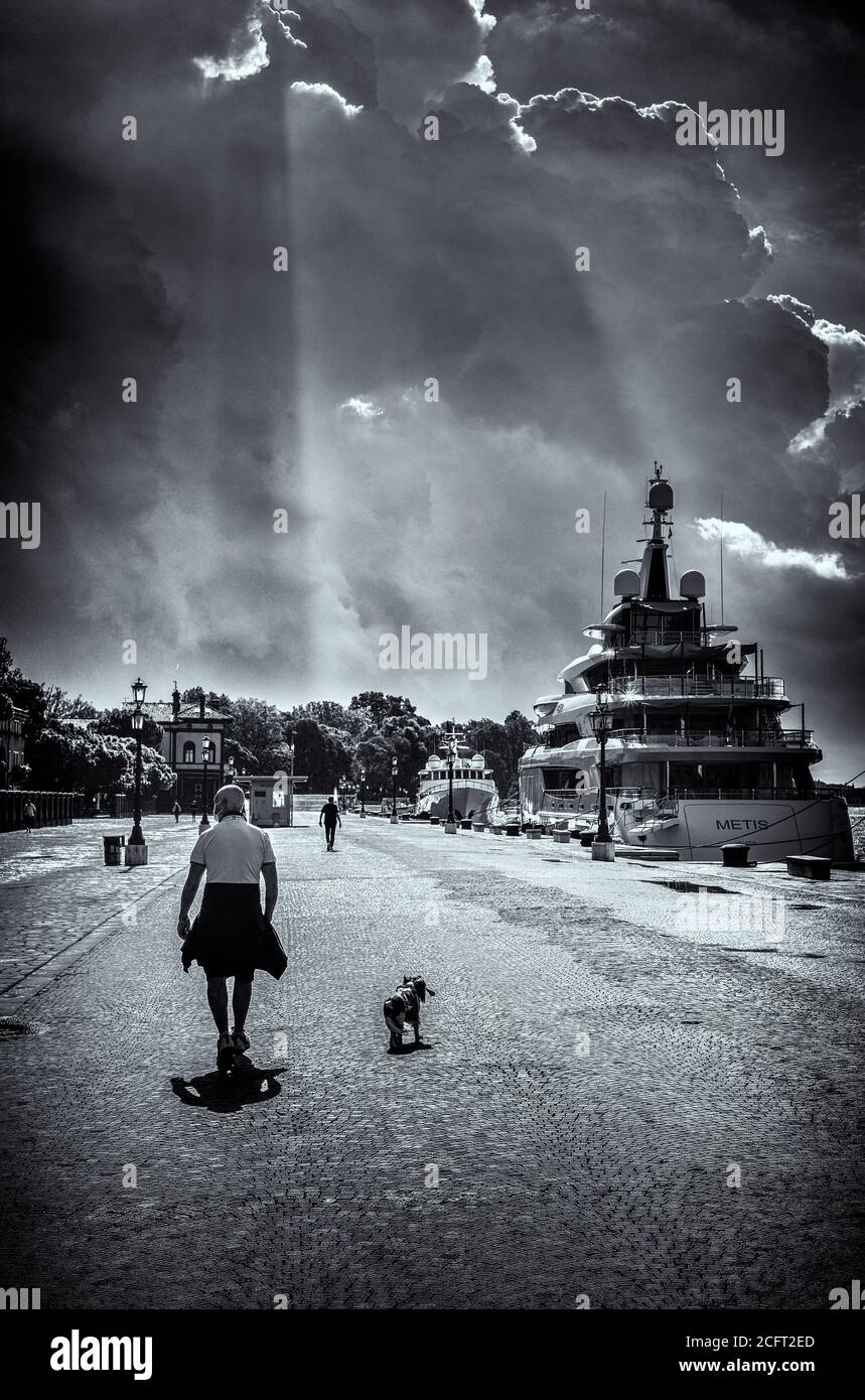 Atmosphere around Venice International Film Festival  on Monday 7 September 2020 at Giardini della Biennale, Venice. A man walking his dog by the waterfront on the wet streets. Picture by Julie Edwards. Stock Photo