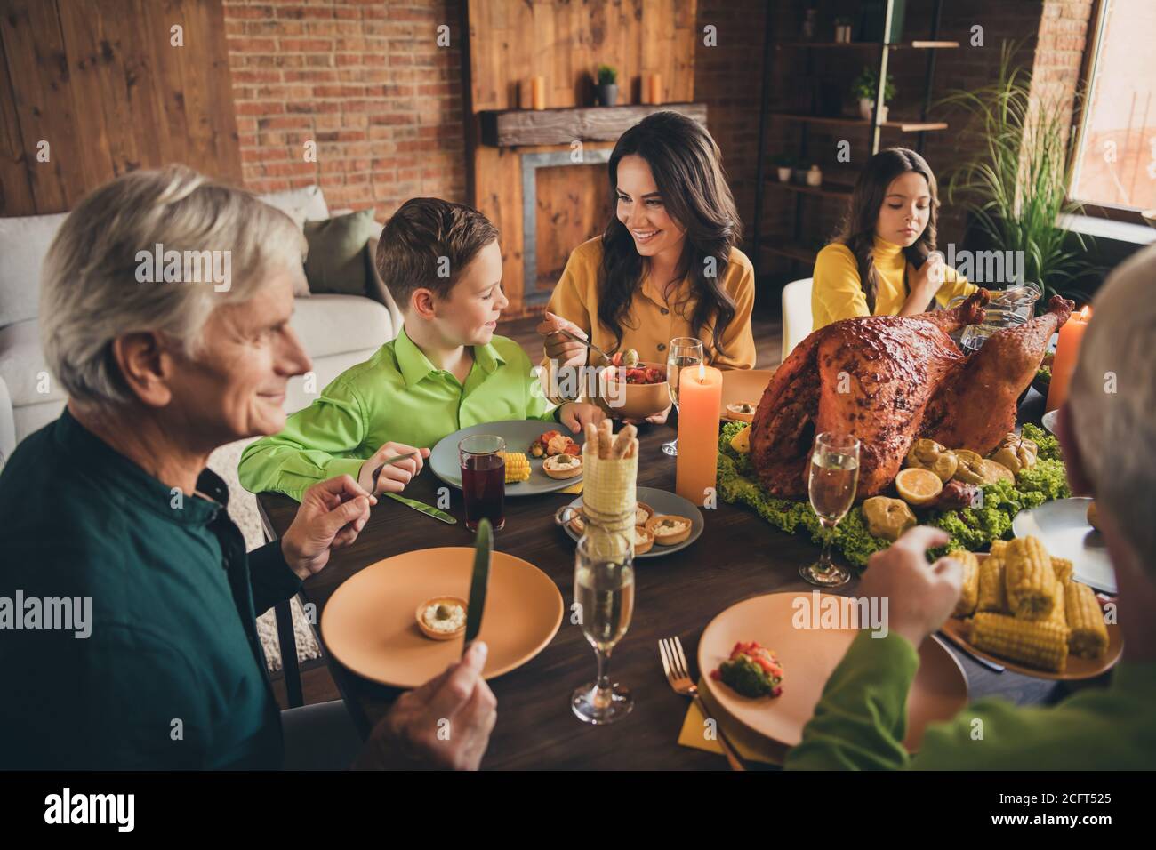 Portrait of nice attractive cheerful family parents grandparents sitting around served table eating homemade tasty delicious fresh dinner meal at Stock Photo