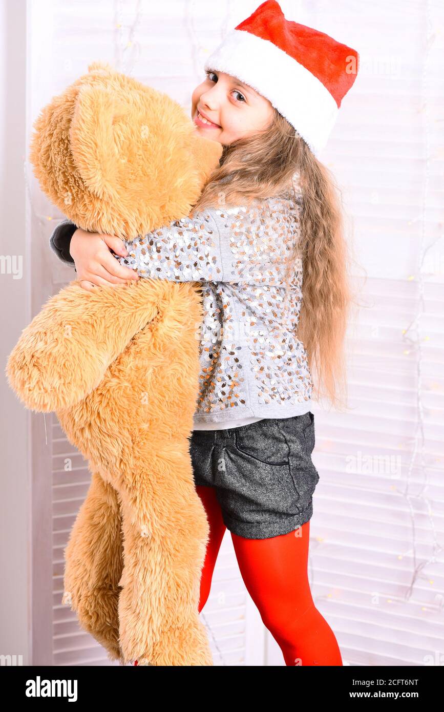 Miss Santa in red hat hugs huge toy bear. Kid gets Christmas present ...