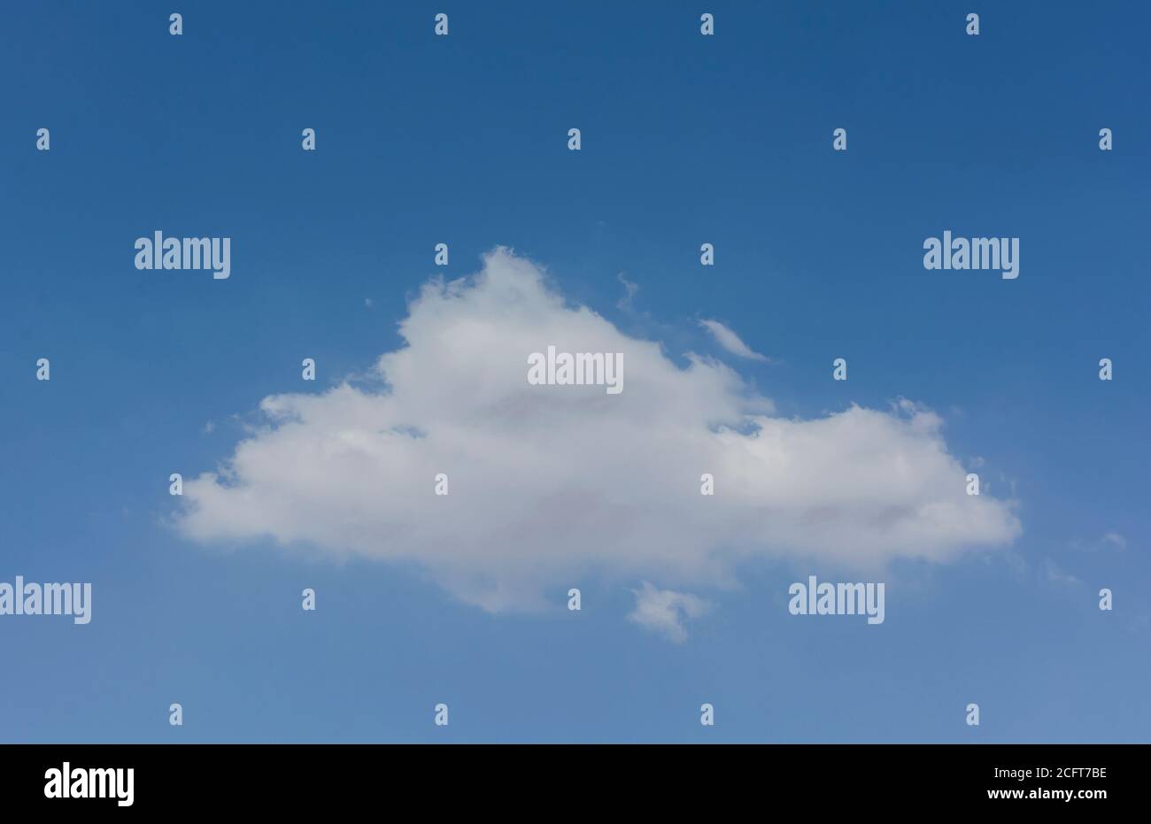 a single small soft and fluffy triangular shaped cumulus cloud in a pure azure blue sky Stock Photo