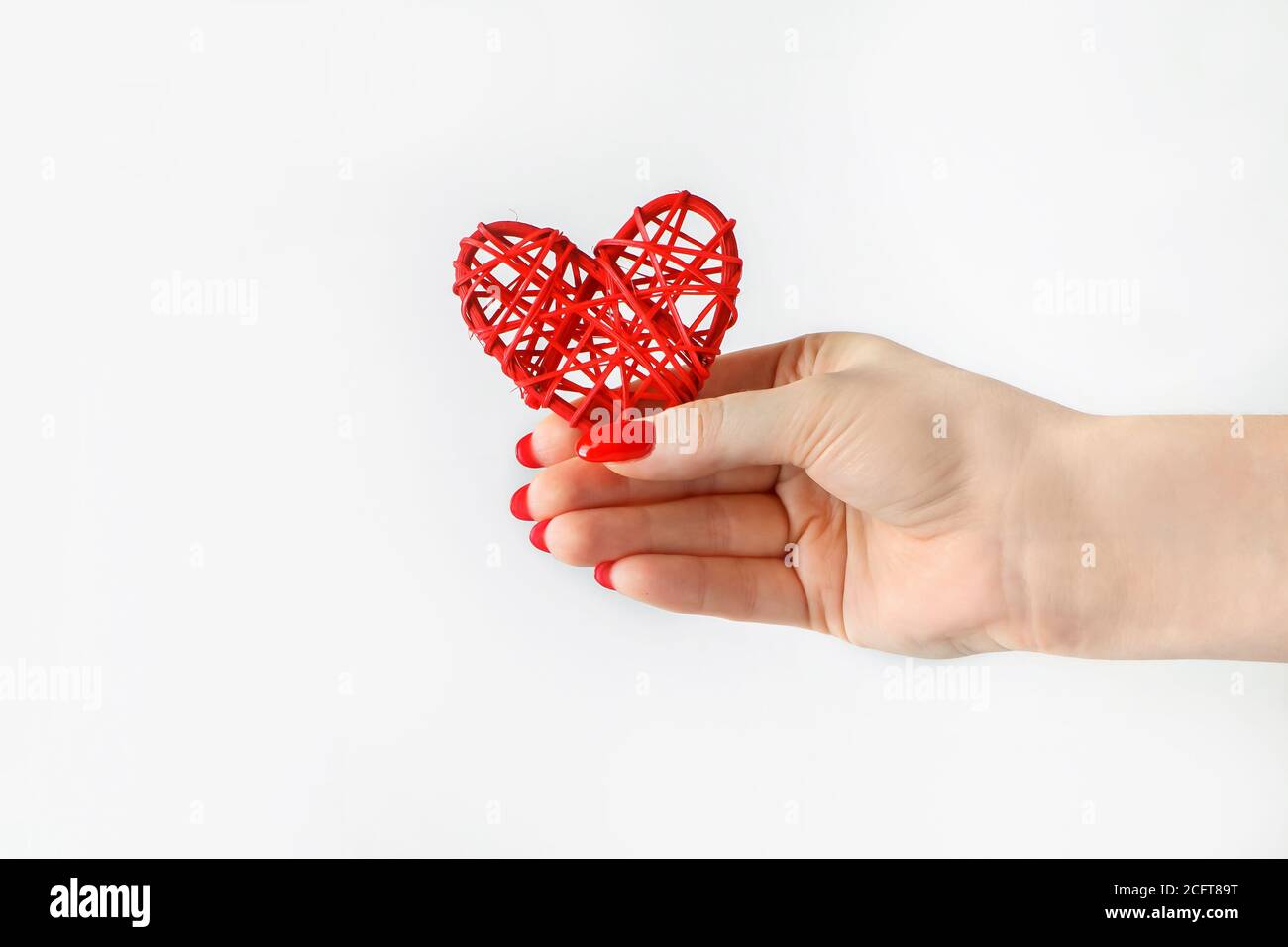 Red heart in his outstretched hand on a white background. A hand holds out a heart. Symbol of cardiology and medicine. Health concept. Stock Photo