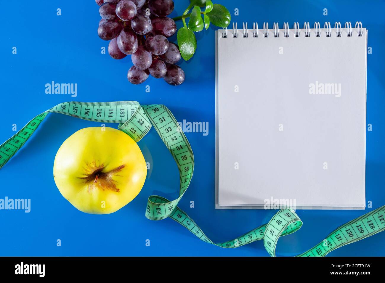 The concept of diet and proper nutrition. Fruits and measuring tape on a blue background.  Layout for design, healthy food and lifestyle. Quarantine E Stock Photo