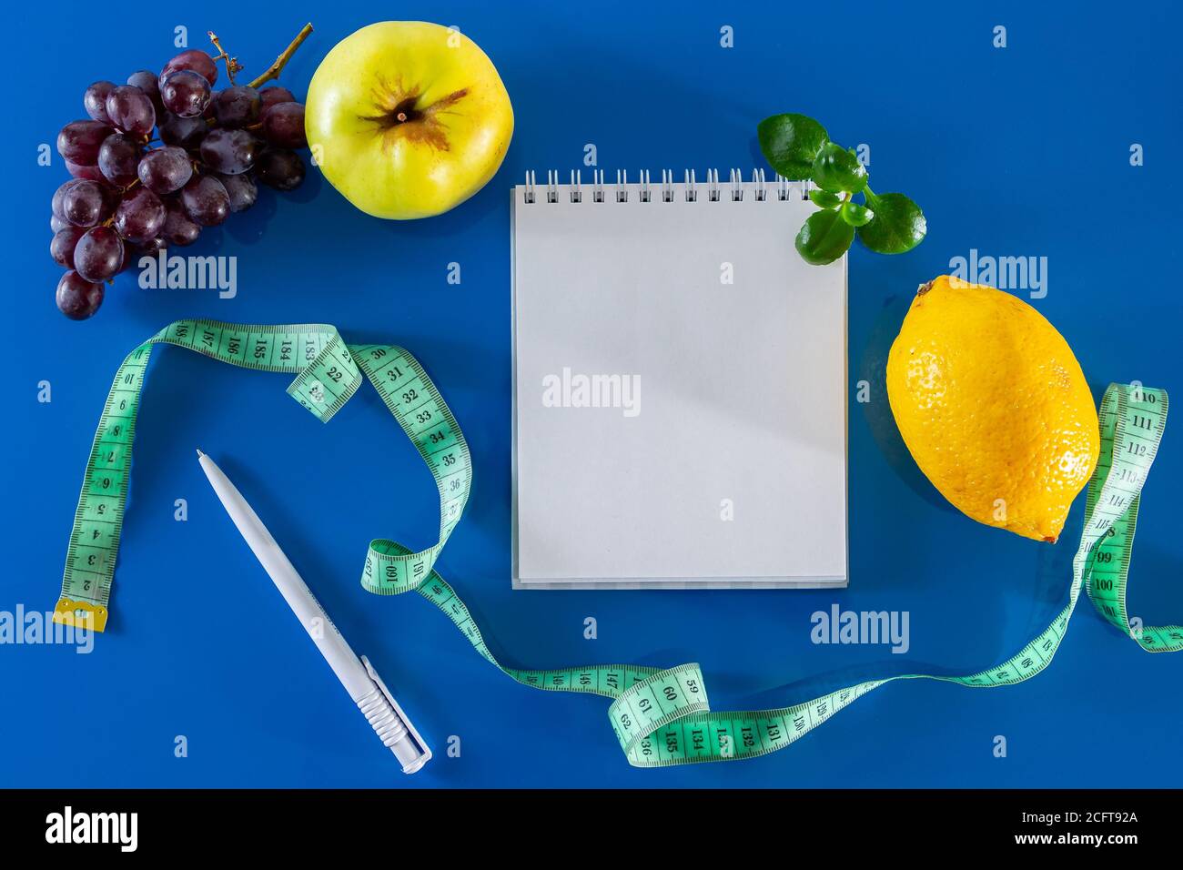 The concept of diet and proper nutrition. Fruits and measuring tape on a blue background.  Layout for design, healthy food and lifestyle. Quarantine E Stock Photo