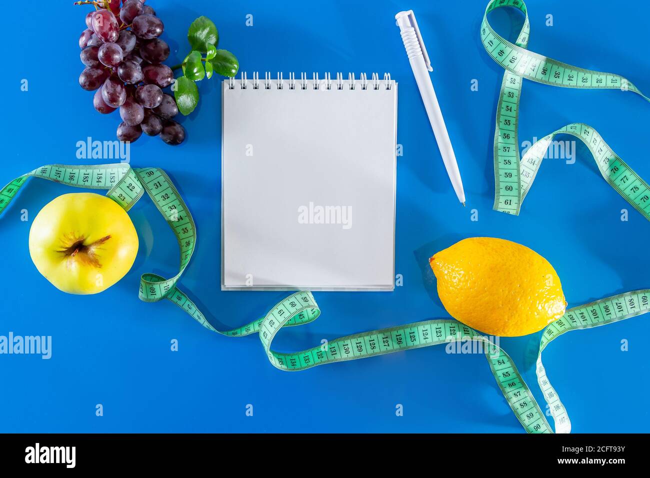 The concept of diet and proper nutrition. Fruits and measuring tape on a blue background.  Layout for design, healthy food and lifestyle. Quarantine E Stock Photo