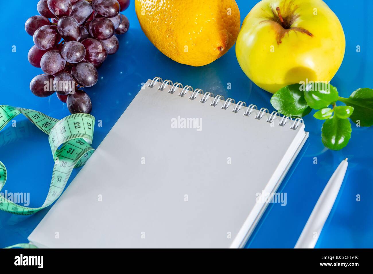 The concept of diet and proper nutrition. Fruits and measuring tape on a blue background.  Layout for design, healthy food and lifestyle. Quarantine E Stock Photo