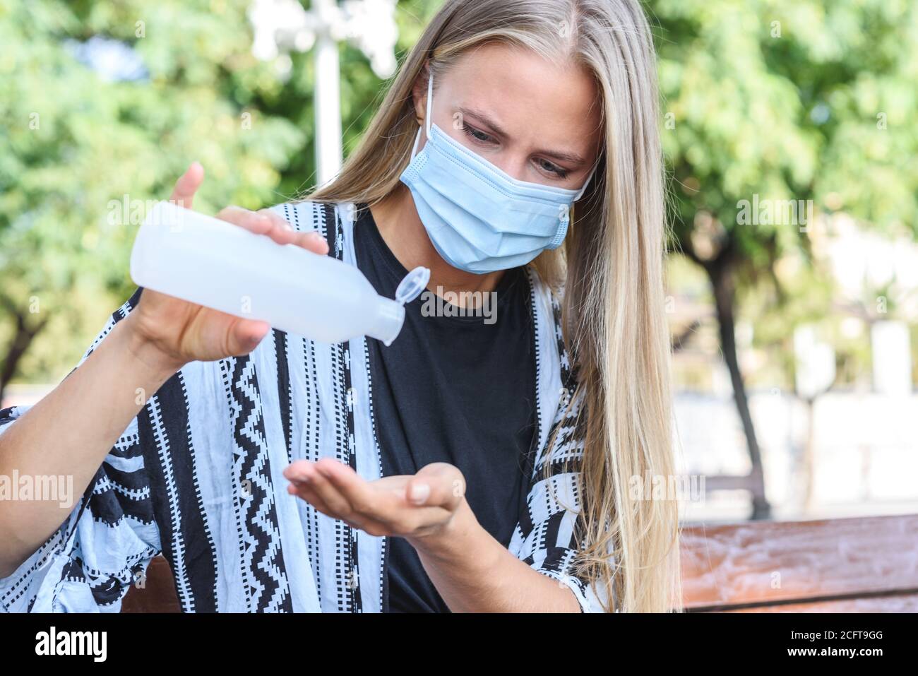 young caucasian blonde woman cleaning her hands with hydroalcoholic gel Stock Photo