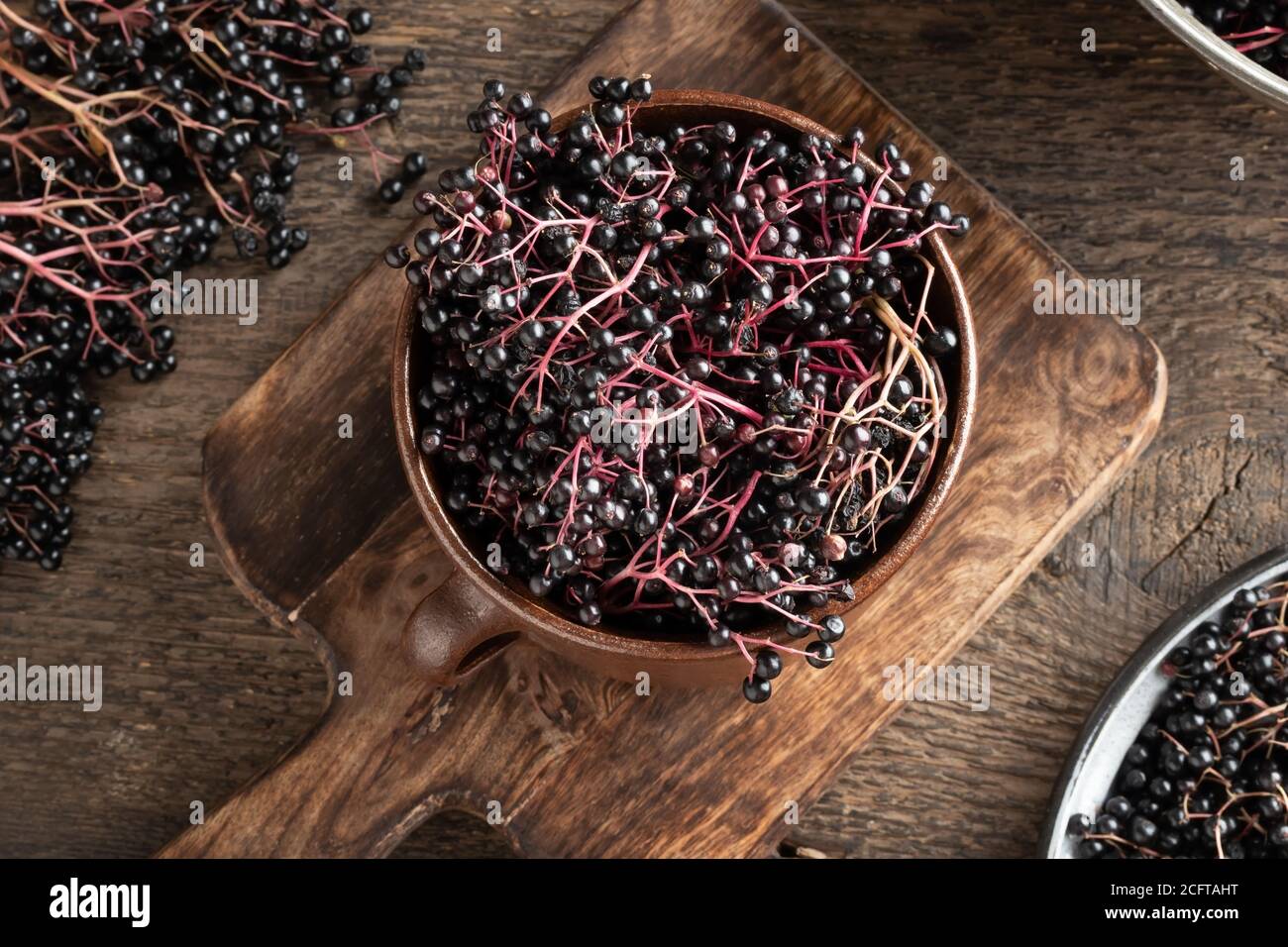 Black elder berries in a brown ceramic pot, top view Stock Photo