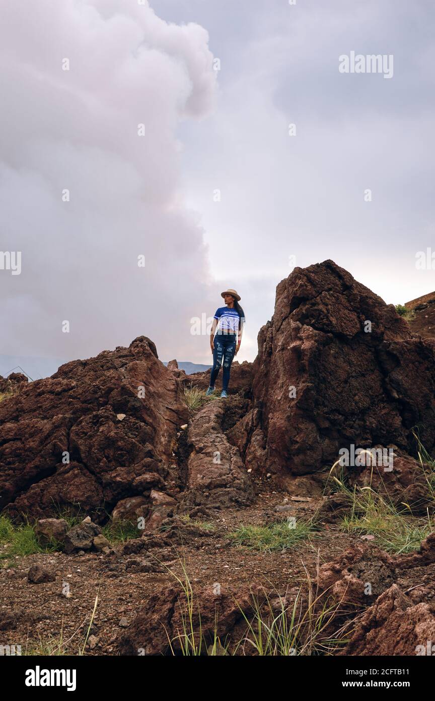 A female wearing a hat standing on huge volcanic rock next to the ...