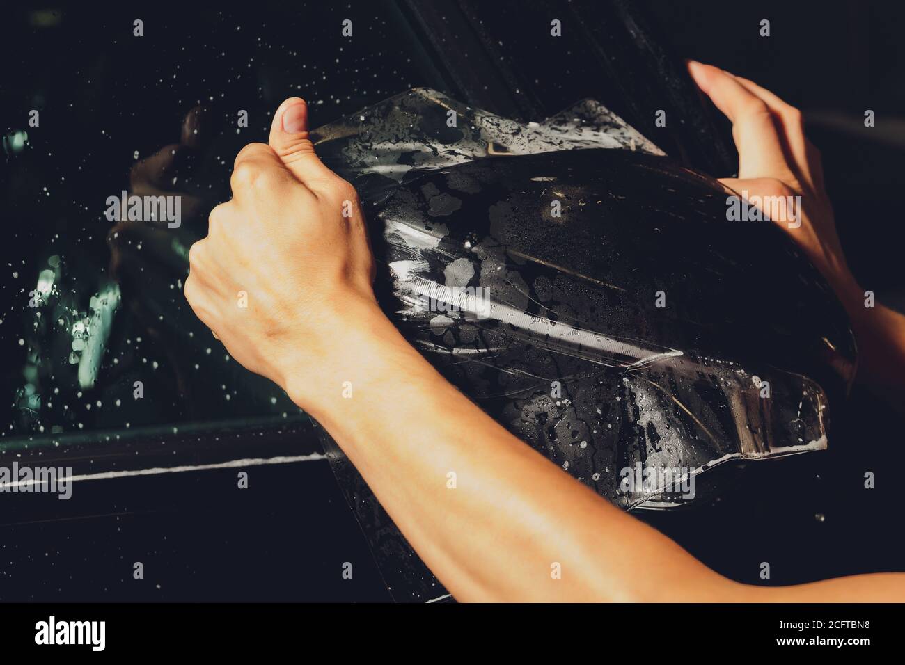 Close up of paint protection film installation on side mirror of modern luxury car. PPF is