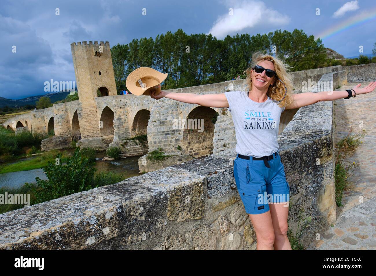 Tourist woman with a hat and medieval bridge and Ebro river. Stock Photo