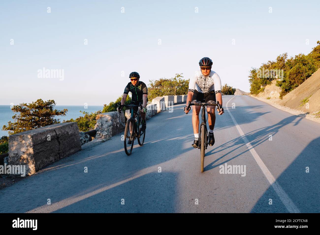 Two professional male cyclists riding their racing bicycles in the ...