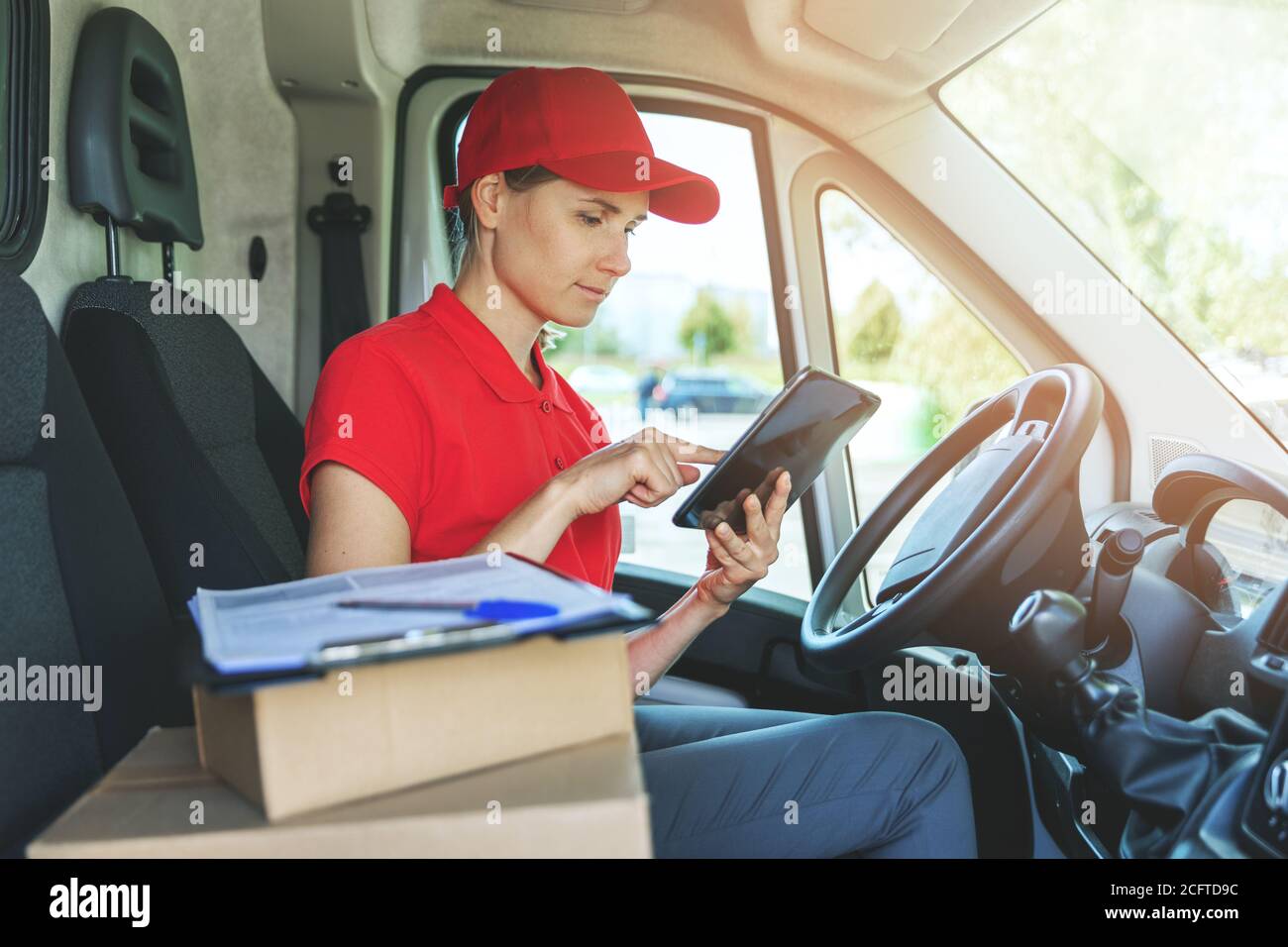 delivery woman using digital tablet while sitting in van Stock Photo