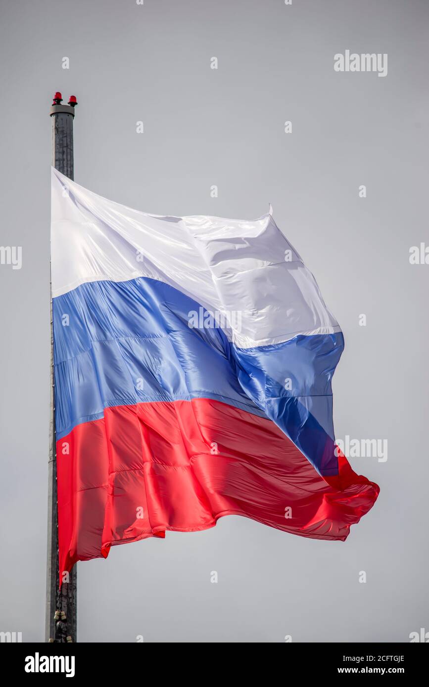 Russian flag against the background of a cloudy sky, waving in the wind. Stock Photo
