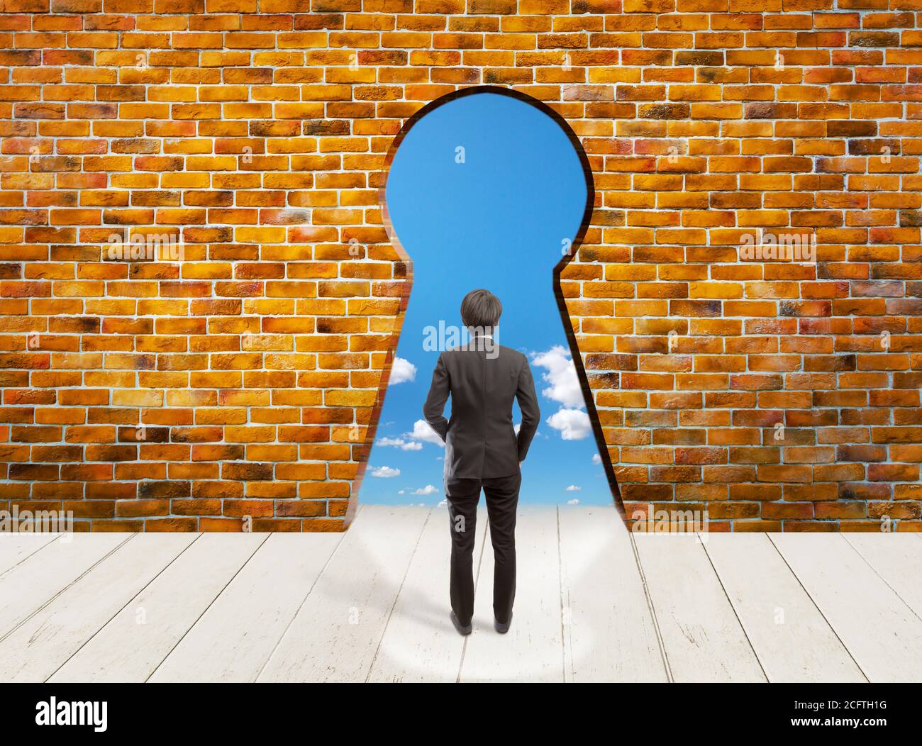 Business man stand in front of  key hold on the brick wall background and white floor with blue sky on the outside, new opportunity is the key to succ Stock Photo