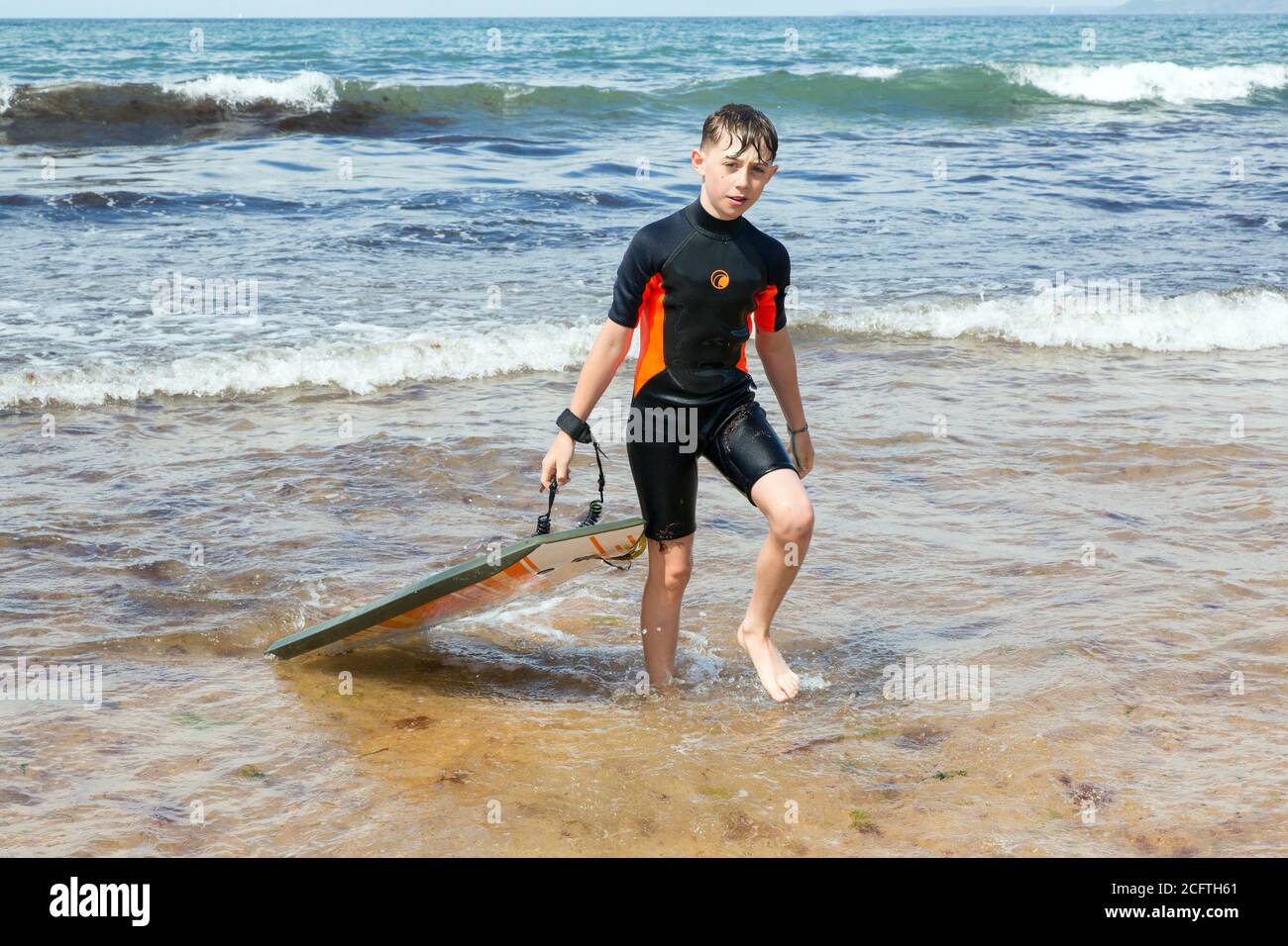 Eleven year old boy surfing at Hope Cove beach, Kingsbridge, Devon, England, United Kingdom. Stock Photo