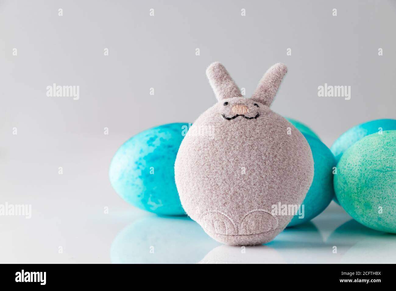 Blue easter eggs and toy rabbit on a white background. Cute toy easter ...