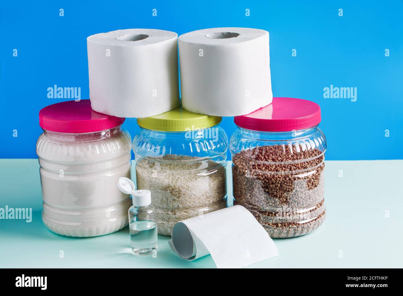 Concept panic buying food at a quarantine - toilet paper, food, antiseptic on a blue background. The coronavirus epidemic in the world. Stock Photo