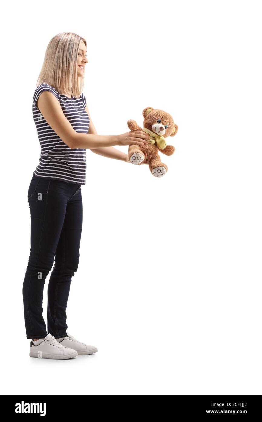 Full length profile shot of a young blond woman giving a teddy bear toy isolated on white background Stock Photo