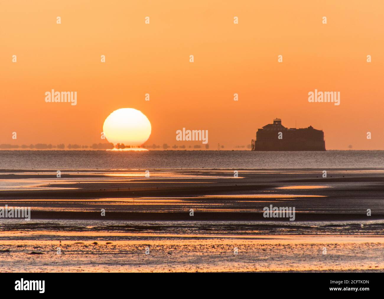 Solent Sunrise. The sun rising beside the No Man's Land Fort in the Solent, photographed from Ryde Pier, Isle of Wight Stock Photo