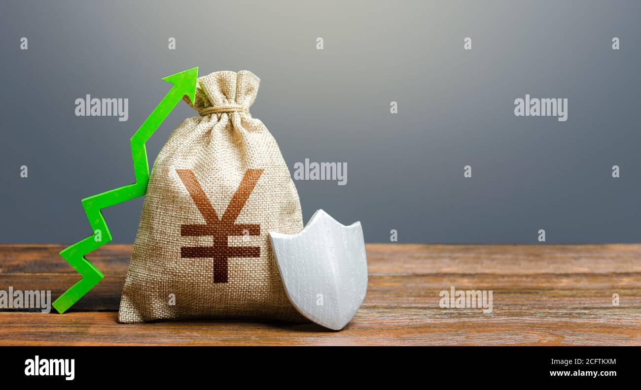 Yen Yuan money bag with a shield and a green arrow up. Safety security of investments, financial system stability. Increasing maximum amount of guaran Stock Photo