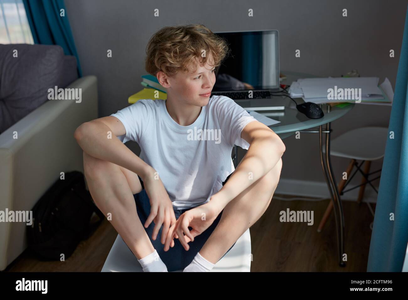 young caucasian redhead boy have rest at home, has some free time after studying, school. sits looking away, take a break. at home Stock Photo