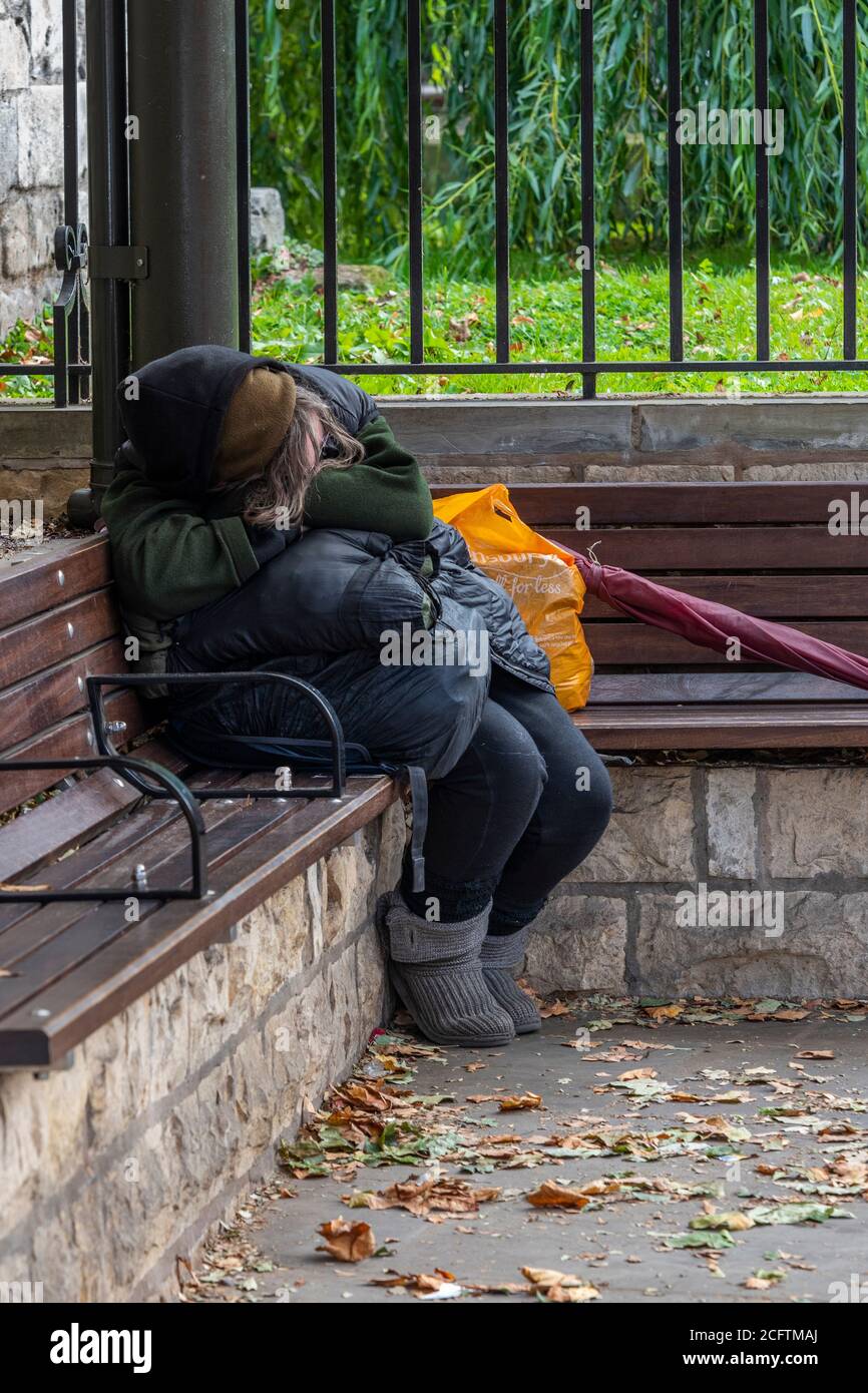 a homeless lady fast asleep on a bench in the centre of the city of york. Stock Photo