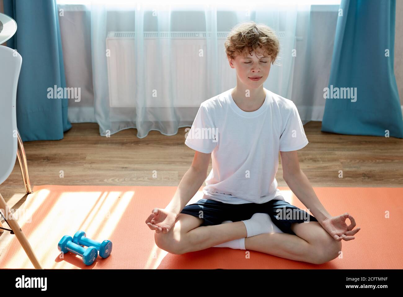 young caucasian teen boy exercising sport at home, practice yoga, sit in pose, keep calm, meditating Stock Photo