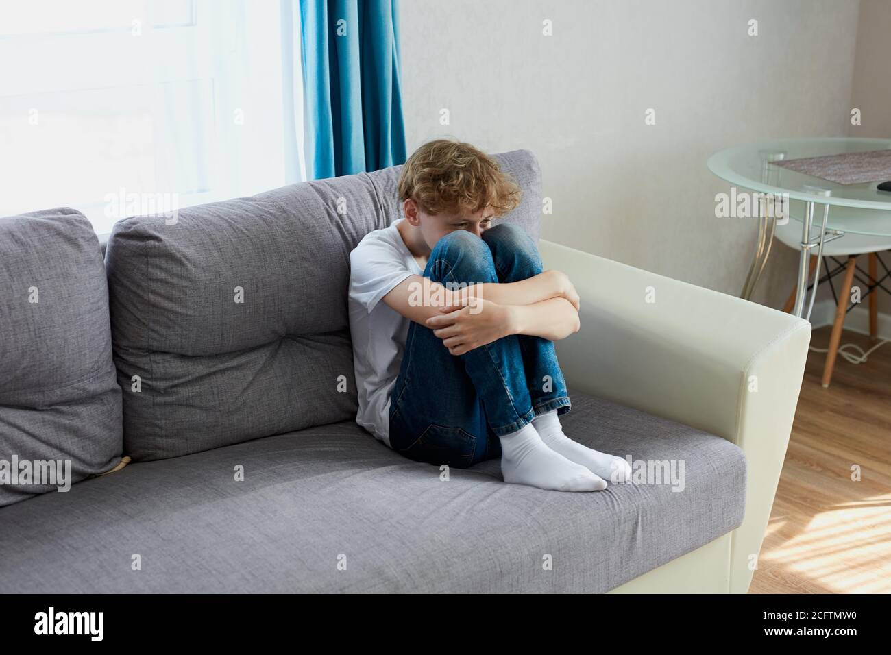 sad child boy sit crying alone at home. school boy suffer from autism Stock Photo