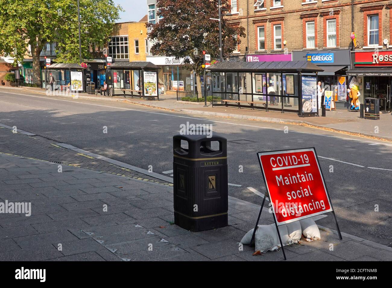 Covid 19 maintain social distancing sign empty deserted Brentwood Essex shopping high street 9.28am weekday town bus stop in coronavirus lockdown UK Stock Photo
