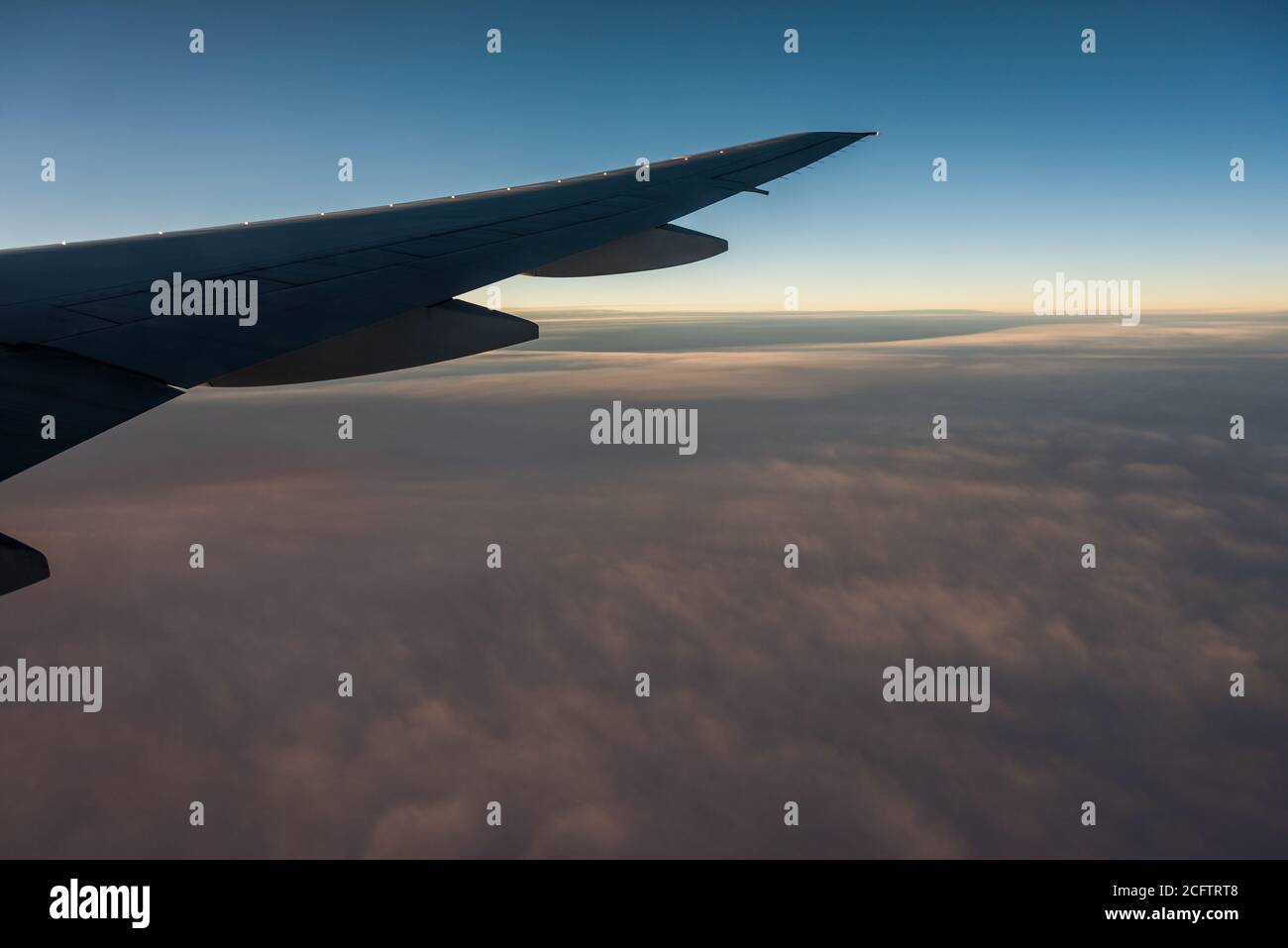 Aerial View from an Airplane. Flying above Clouds at Sunrise Stock Photo