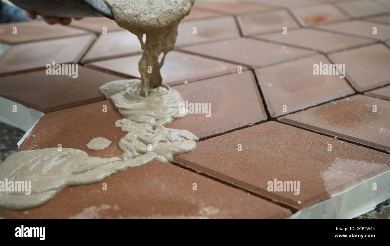 Filling paving slabs with a solution on the street. The builder fills
