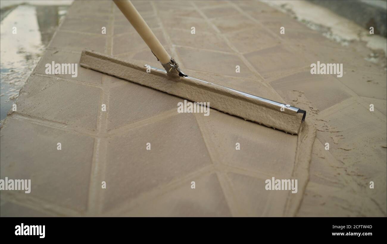 Worker hand with bucket pouring cement for tiles installation making on