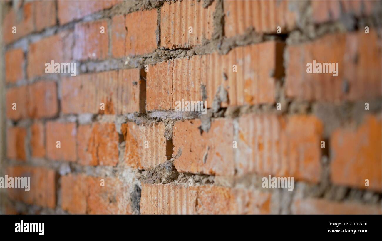 he moistening the surface before applying plaster. The process of priming a brick wall. A primer