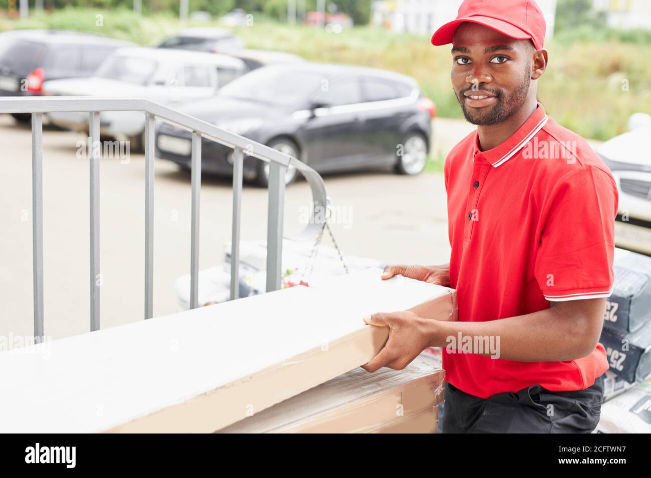 young african black man work in delivery company, came to clients to give  it, wearing red uniform Stock Photo - Alamy