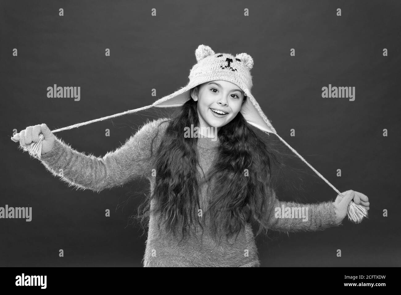 Cute model enjoy winter style. Teddy bear. Being cute bear. Winter outfit. Little kid wear knitted hat. Stay warm. Little girl winter fashion accessory. Small child long hair wear hat red background Cute model enjoy winter style. Teddy bear. Being cute bear. Winter outfit. Little kid wear knitted hat. Stay warm. Little girl winter fashion accessory. Small child long hair wear hat red background