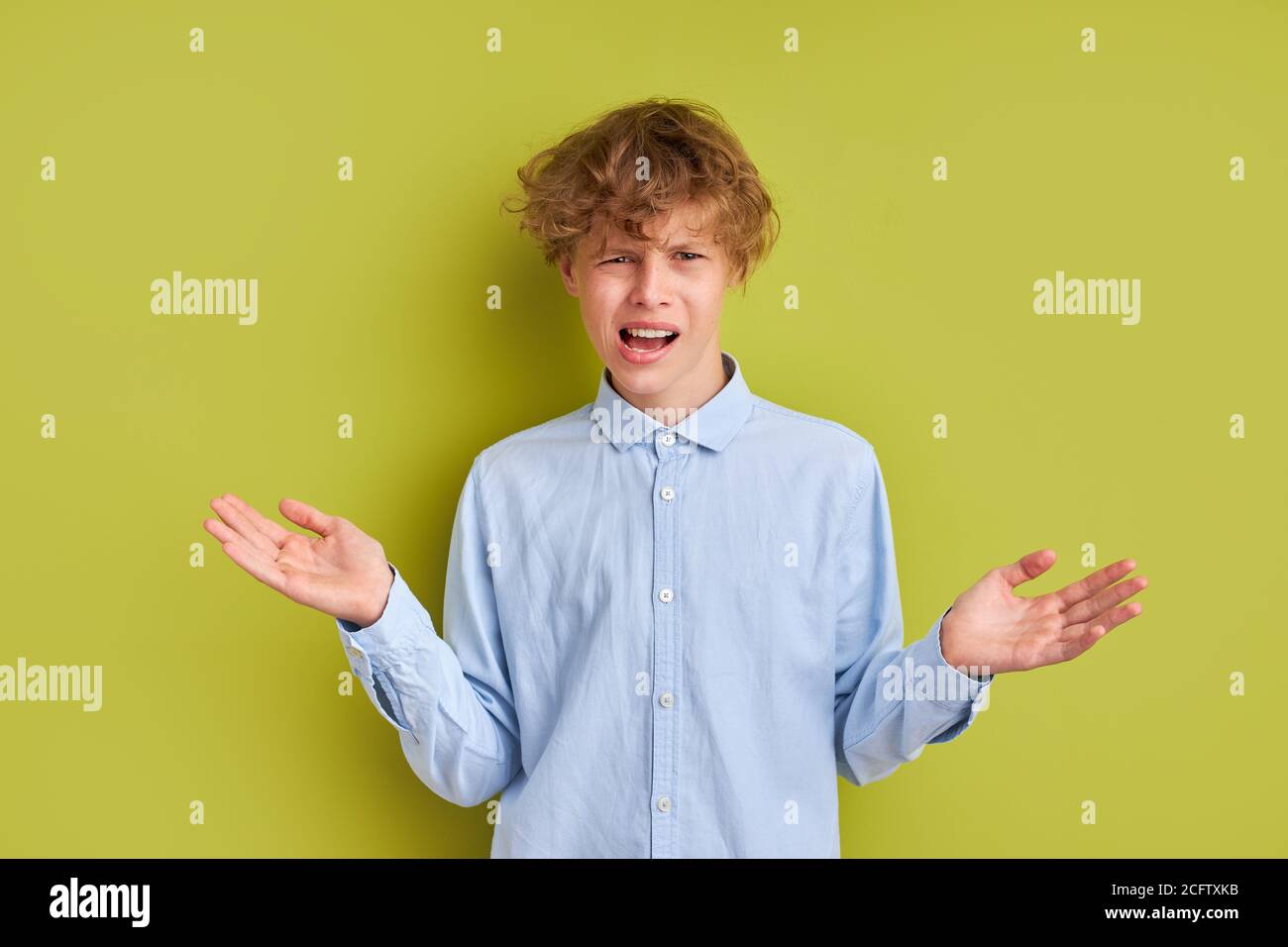 caucasian curly boy misunderstanding something, he is frustrated, emotionally react on news Stock Photo