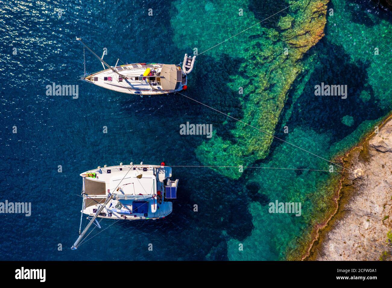 Aerial view of anchored sailing yacht in emerald sea. Aerial view of a