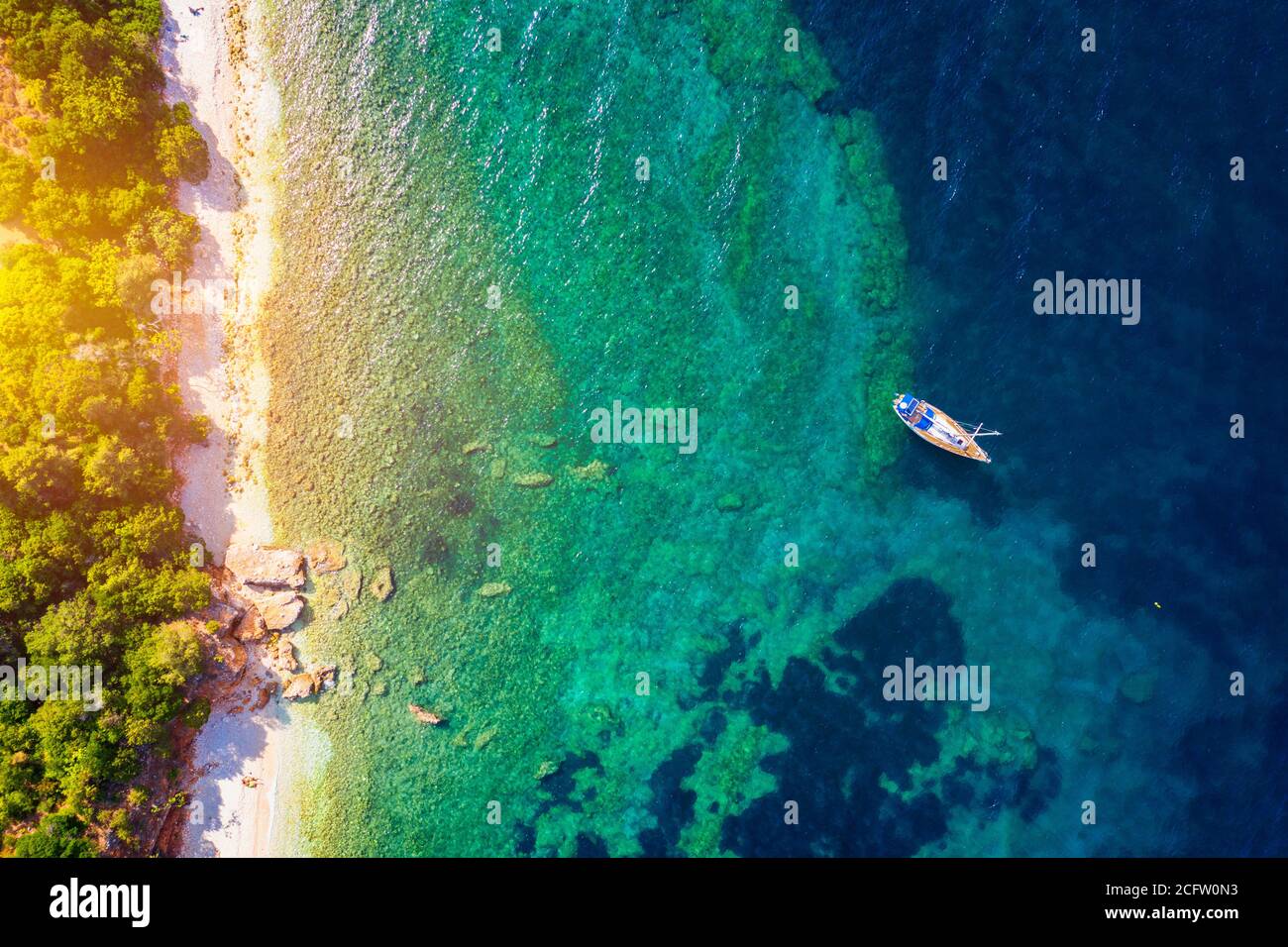 Aerial view of anchored sailing yacht in emerald sea. Aerial view of a